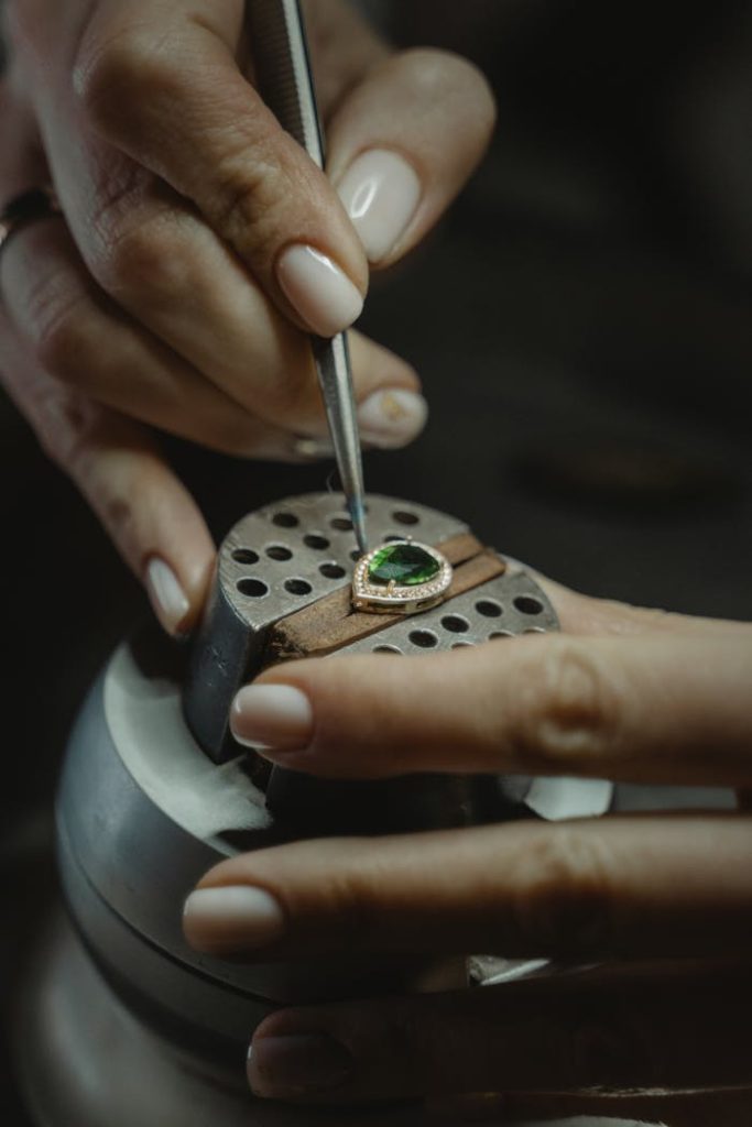 pexels-photo-6263143 A skilled jeweler carefully crafting an emerald ring using a tweezer, showcasing craftsmanship.
